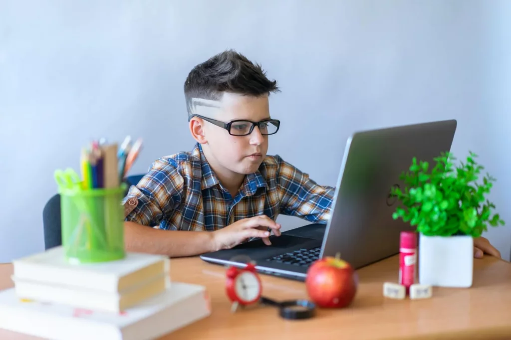 Young student using a laptop and school supplies to practice the active recall study method during online learning