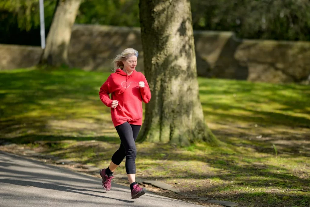 Exercise and Memory: 7 Proven Ways to Use Movement Better Elderly woman jogging in a sunlit park, showing how aerobic exercise for memory supports healthy aging