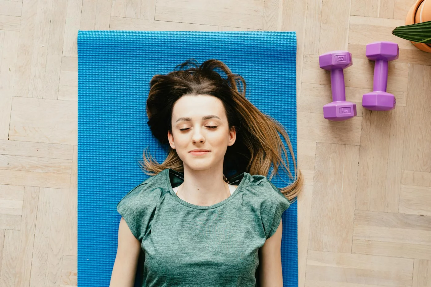 Exercise and Memory: 7 Proven Ways to Use Movement Better Woman resting on a yoga mat beside dumbbells after aerobic exercise for memory and cognitive health