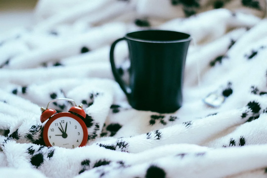 Green ceramic mug by an analog alarm clock, illustrating the Andrew Huberman sleep cocktail bedtime routine
