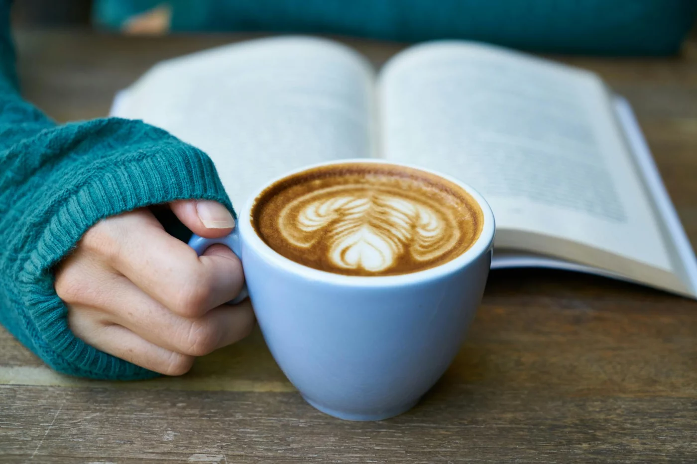 Latte beside an open book illustrating the best time to drink coffee for studying during a focused session