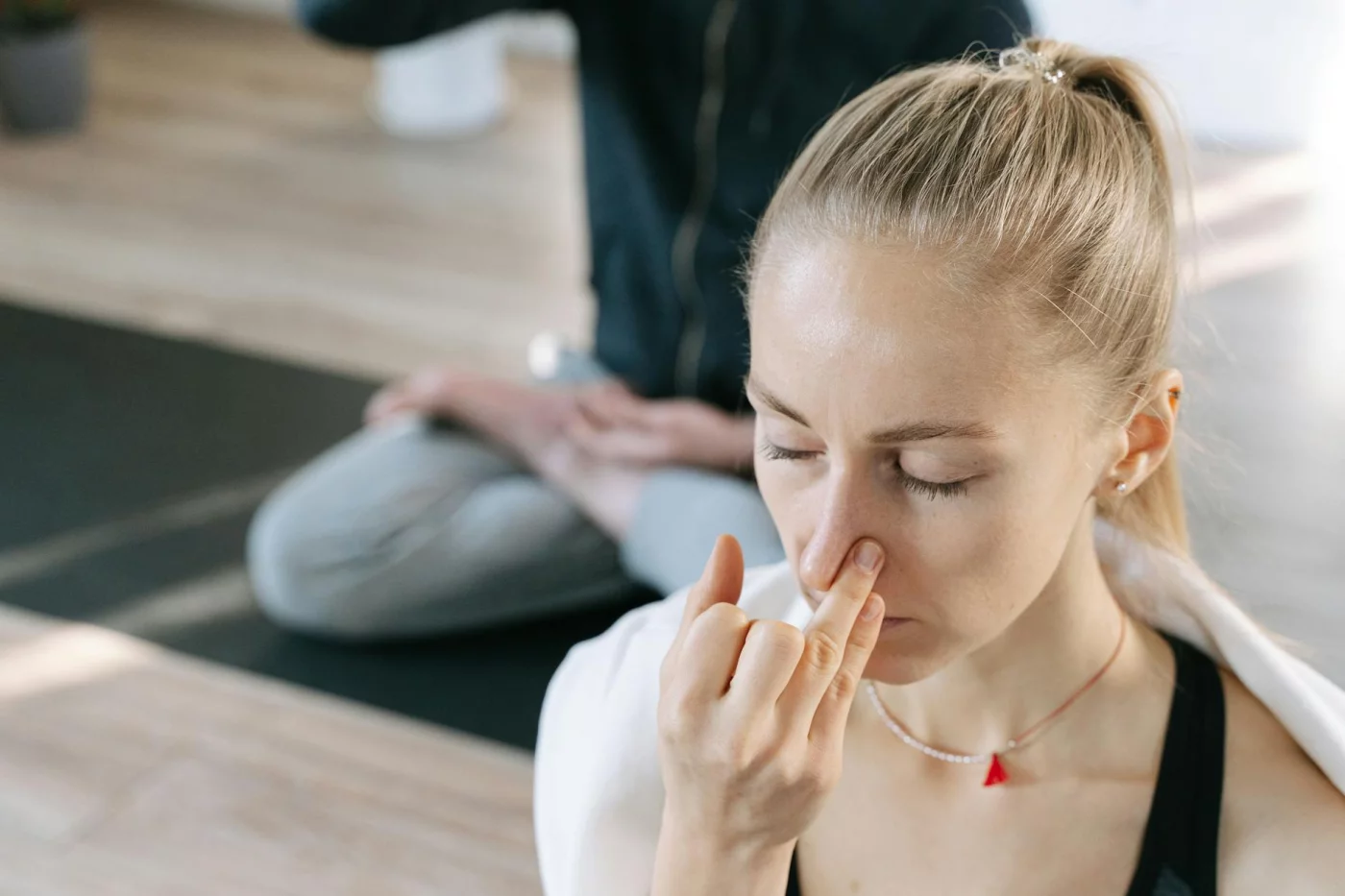 Woman meditating indoors comparing breathing exercises for stress like box breathing, 4-7-8, cyclic sighing, and paced breathing