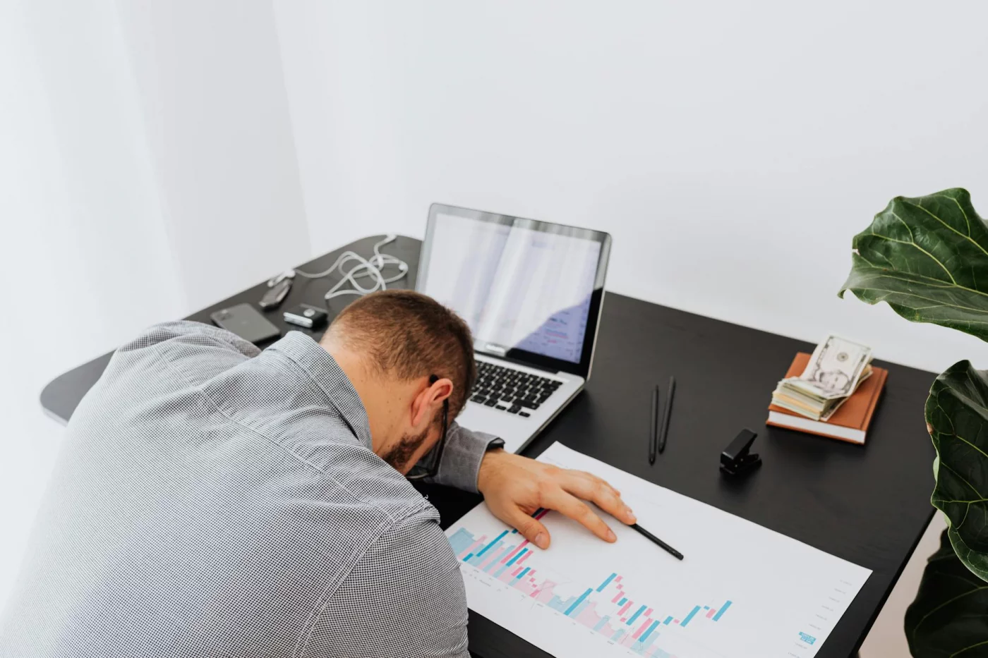 Burnout Statistics by Profession: Patterns and Risks Overworked businessman asleep at his desk beside charts illustrating burnout statistics by profession from 2022 to 2026