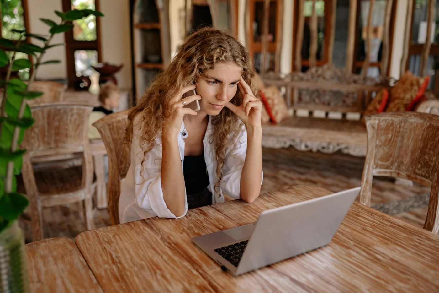 Deep work vs shallow work test: cal newport deep work method as woman multitasks on phone and laptop in rustic room