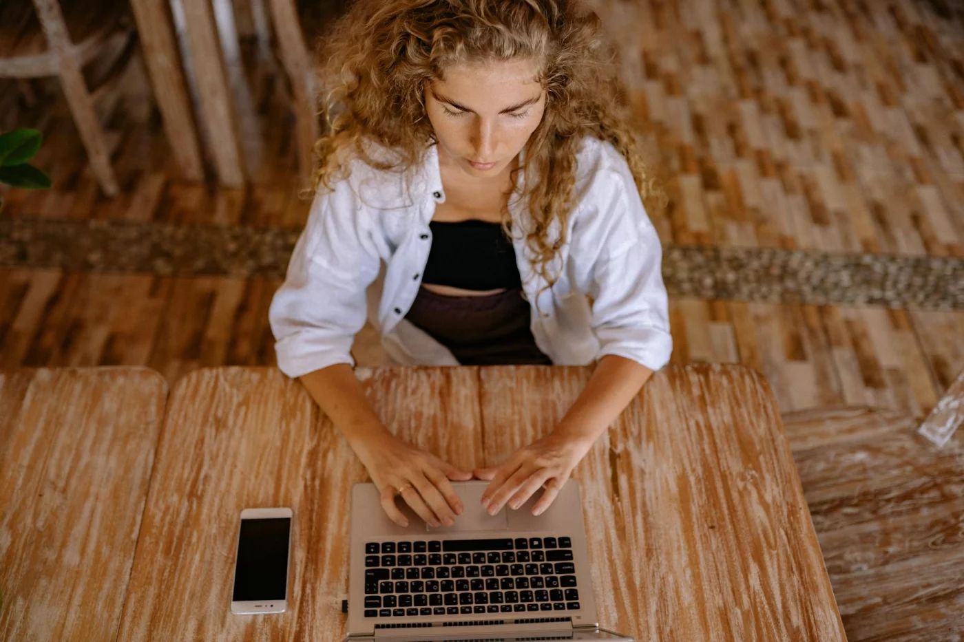 7-step cal newport deep work method protocol and deep work equation shown as woman types on laptop with phone nearby