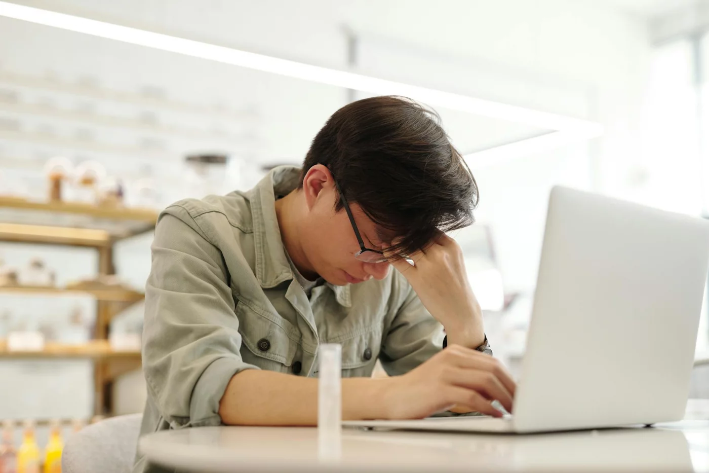 Exhausted man at a laptop illustrates how can high cortisol cause brain fog by affecting focus and memory