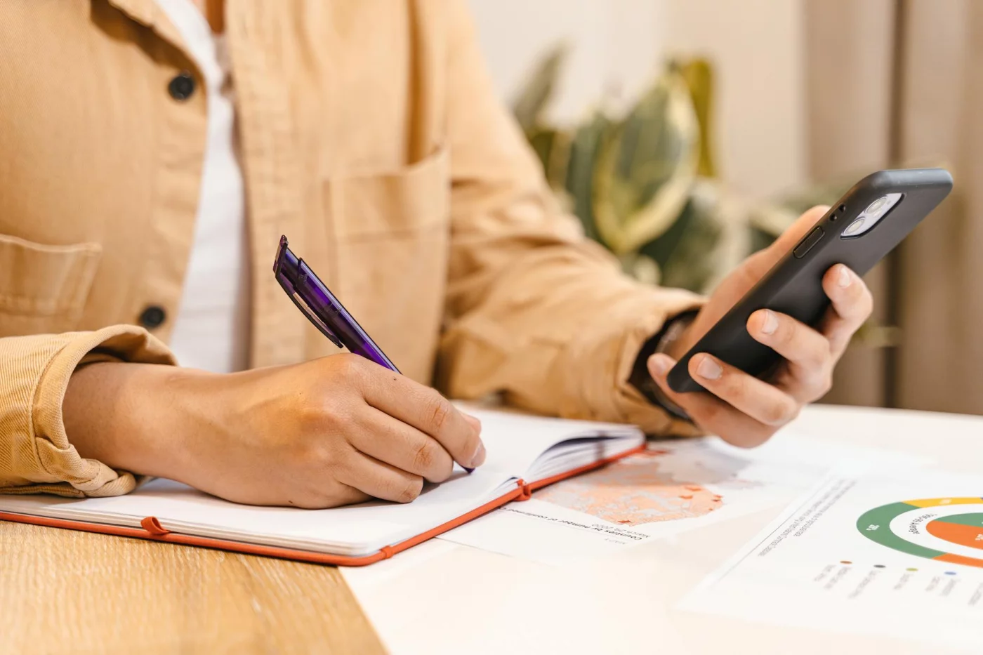 Hands using a smartphone while writing notes, showing context switching—can humans multitask psychology explains the difference
