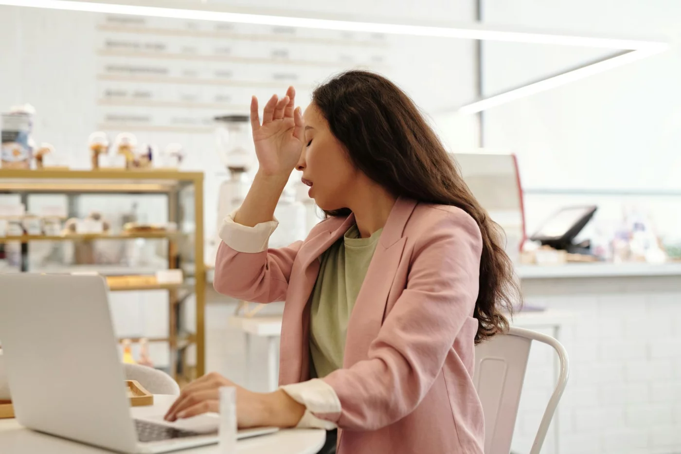 Fatigued woman working on a laptop indoors, illustrating how can stress cause brain fog during daily tasks