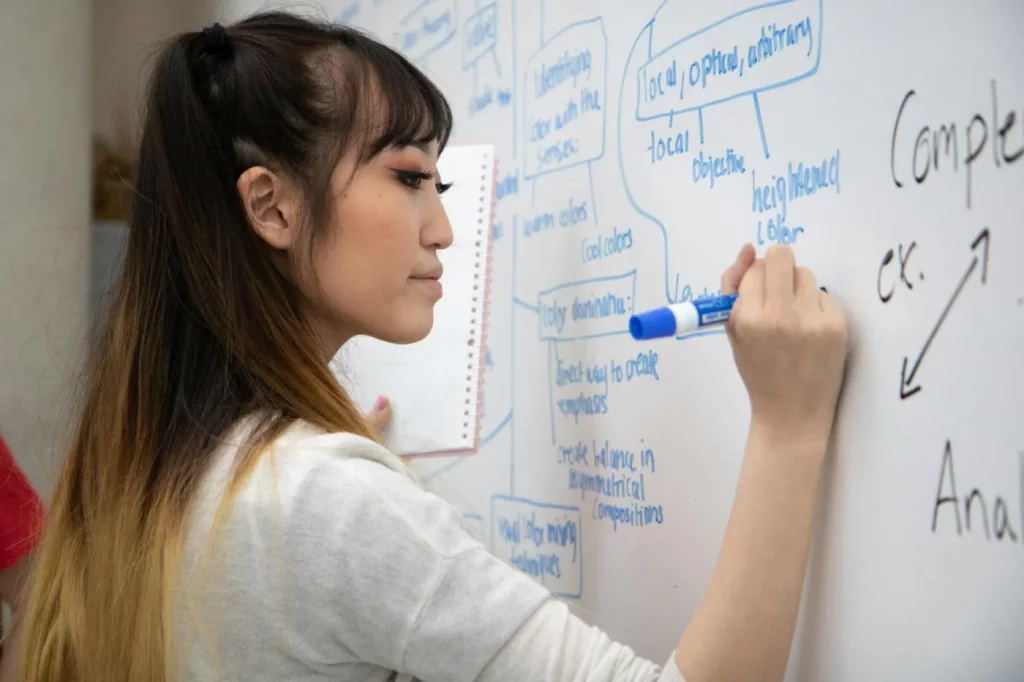 Student comparing cornell notes vs mind mapping lectures reddit ideas while writing on a whiteboard in class