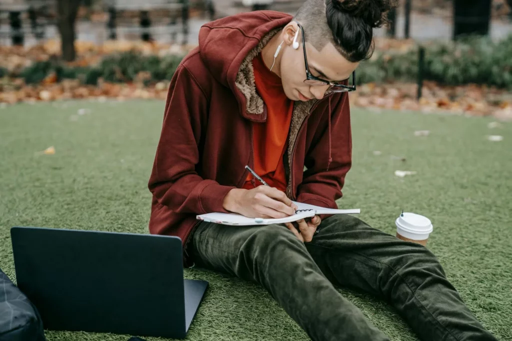 Caffeine and Focus: Dose, Timing, and Study Rules Student studying on grass with laptop and coffee, exploring does caffeine help you focus adhd