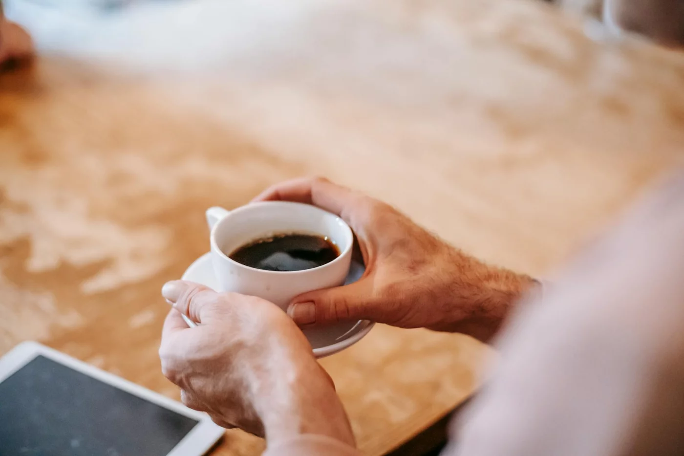 Caffeine and Focus: Dose, Timing, and Study Rules Man drinking coffee with tablet in cafe, does caffeine help you focus adhd while studying and managing dose