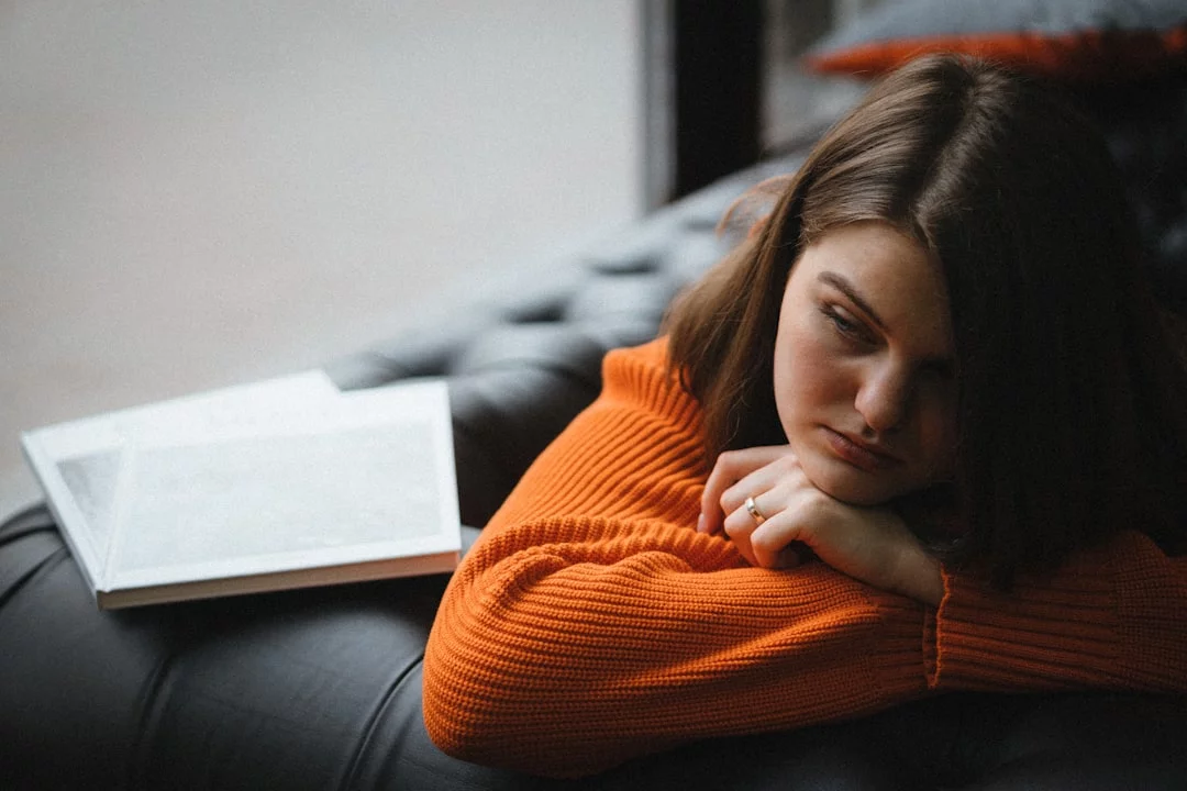 Woman resting on a couch with a book, reflecting on fear of failure and procrastination