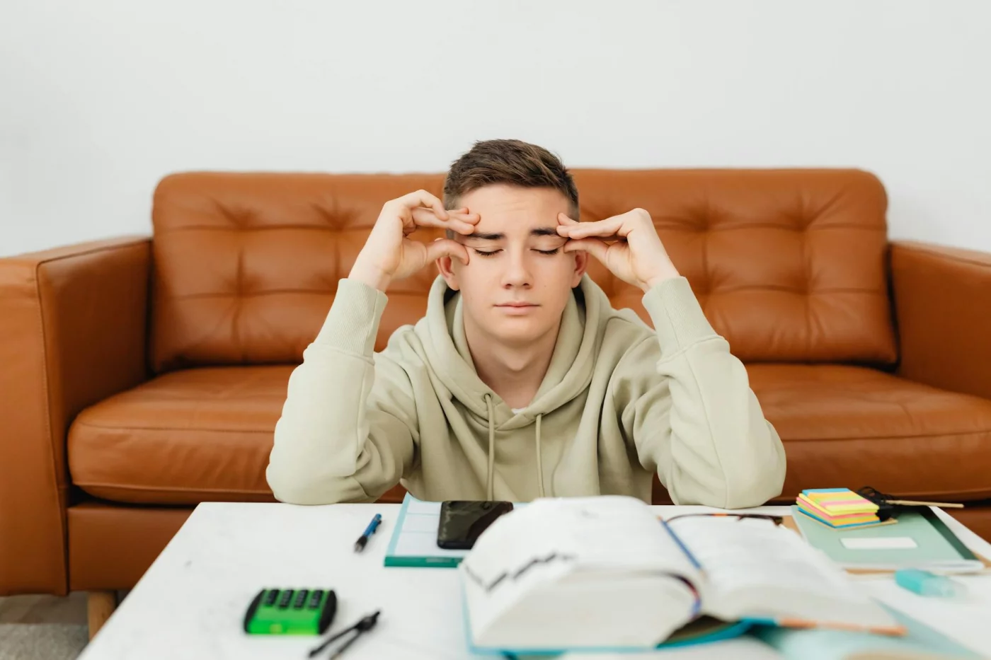 Student in a hoodie feeling overwhelmed at home, reflecting fear of failure and procrastination during study time