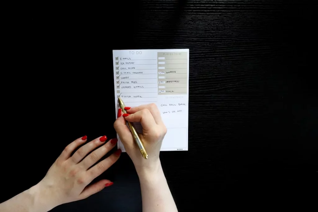 Person writing a habit stacking template on white paper to build daily routines that stick