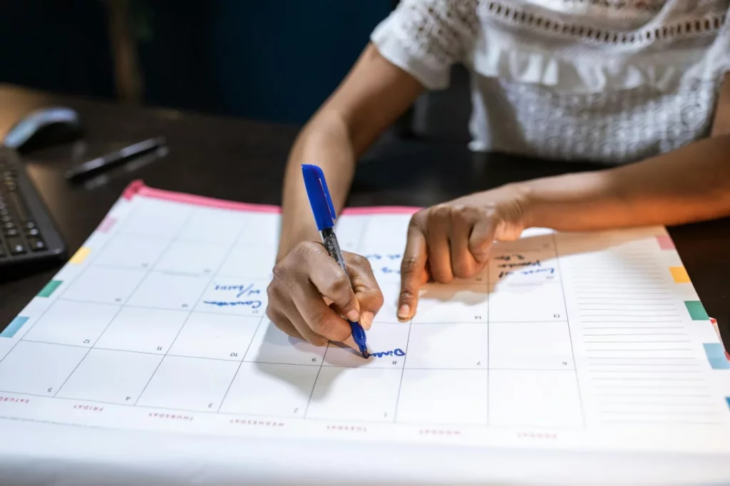 Woman marking dates on a desk calendar while planning how to build new habits that stick