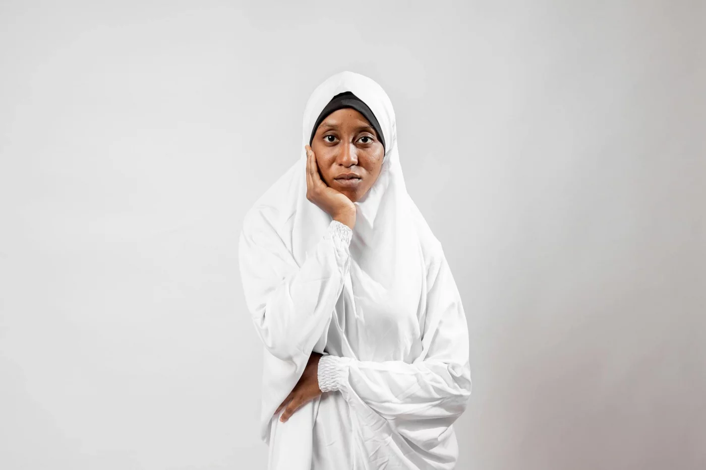 Thoughtful woman in a white hijab illustrating how to do the 5 4 3 2 1 grounding technique for anxiety relief