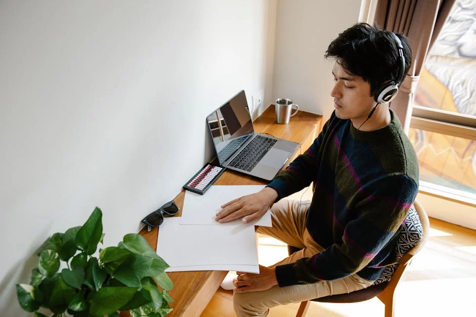 Man in headphones at a plant-filled desk shows how to enhance focus and improve productivity while working on a laptop