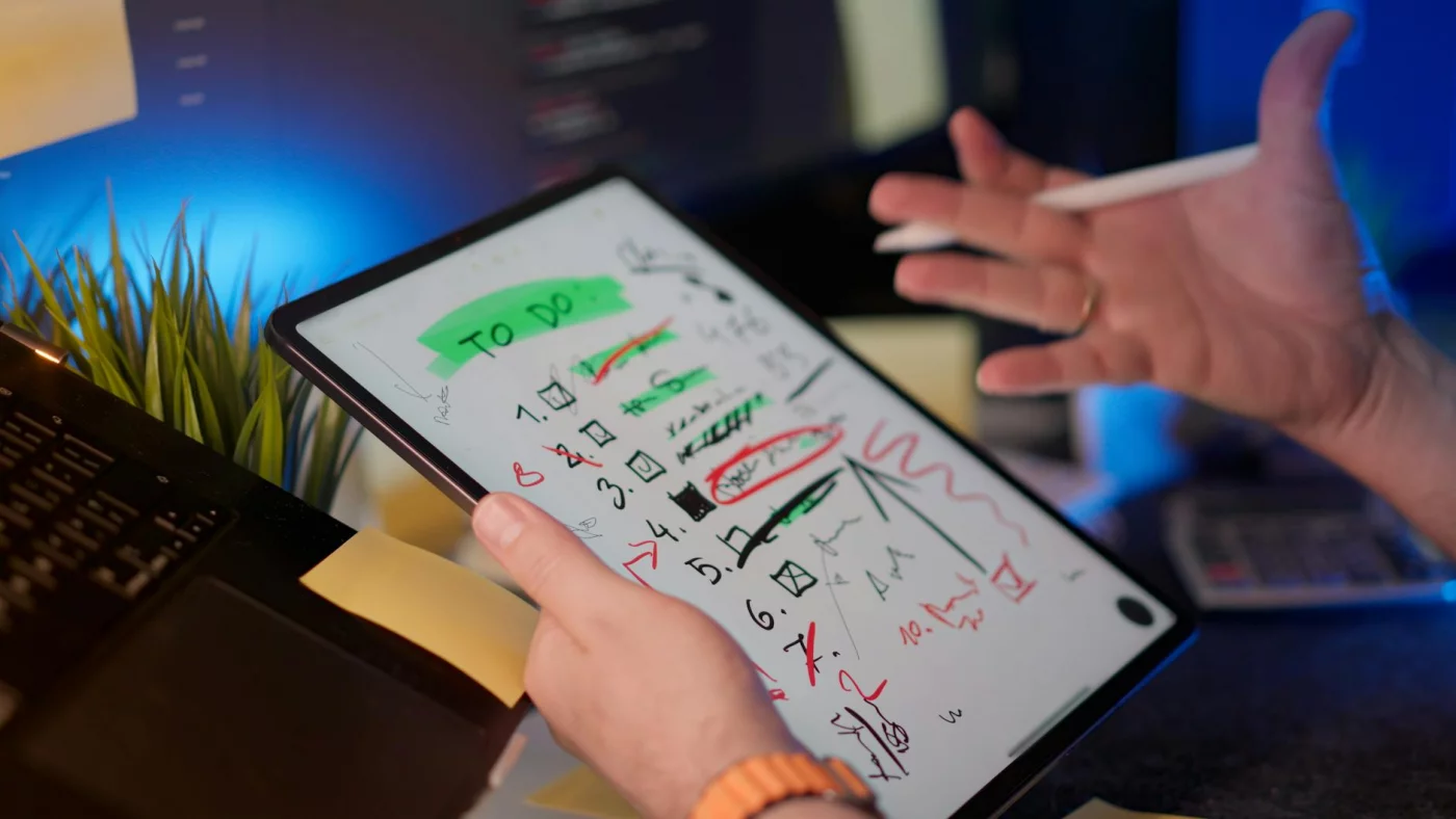 Professional using a tablet and digital pen, showing how to focus in open office environment during daily tasks