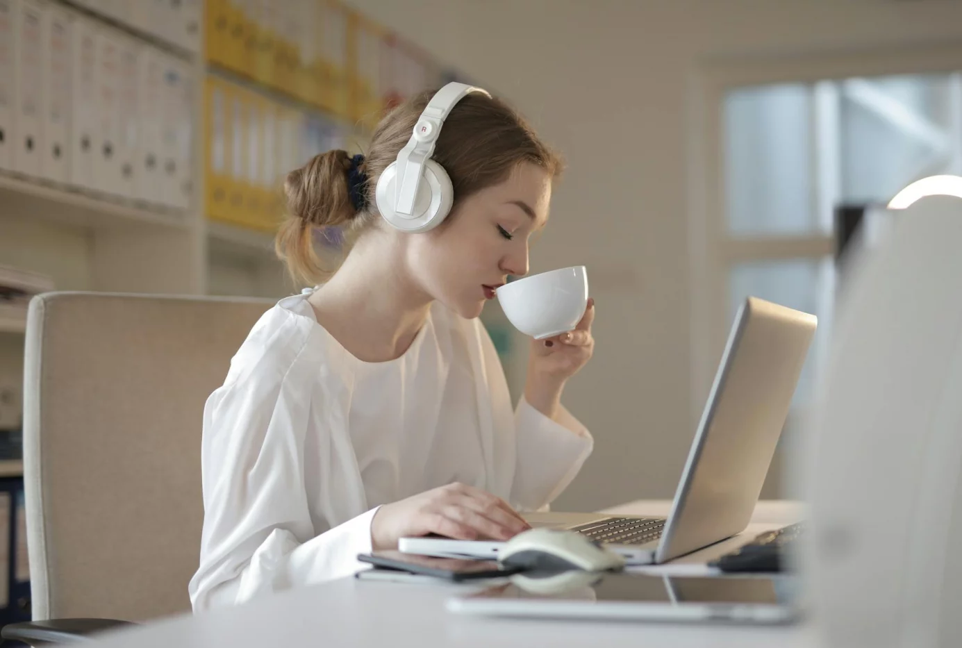 Woman in headphones doing a 5-minute distraction audit to learn how to focus in open office environment
