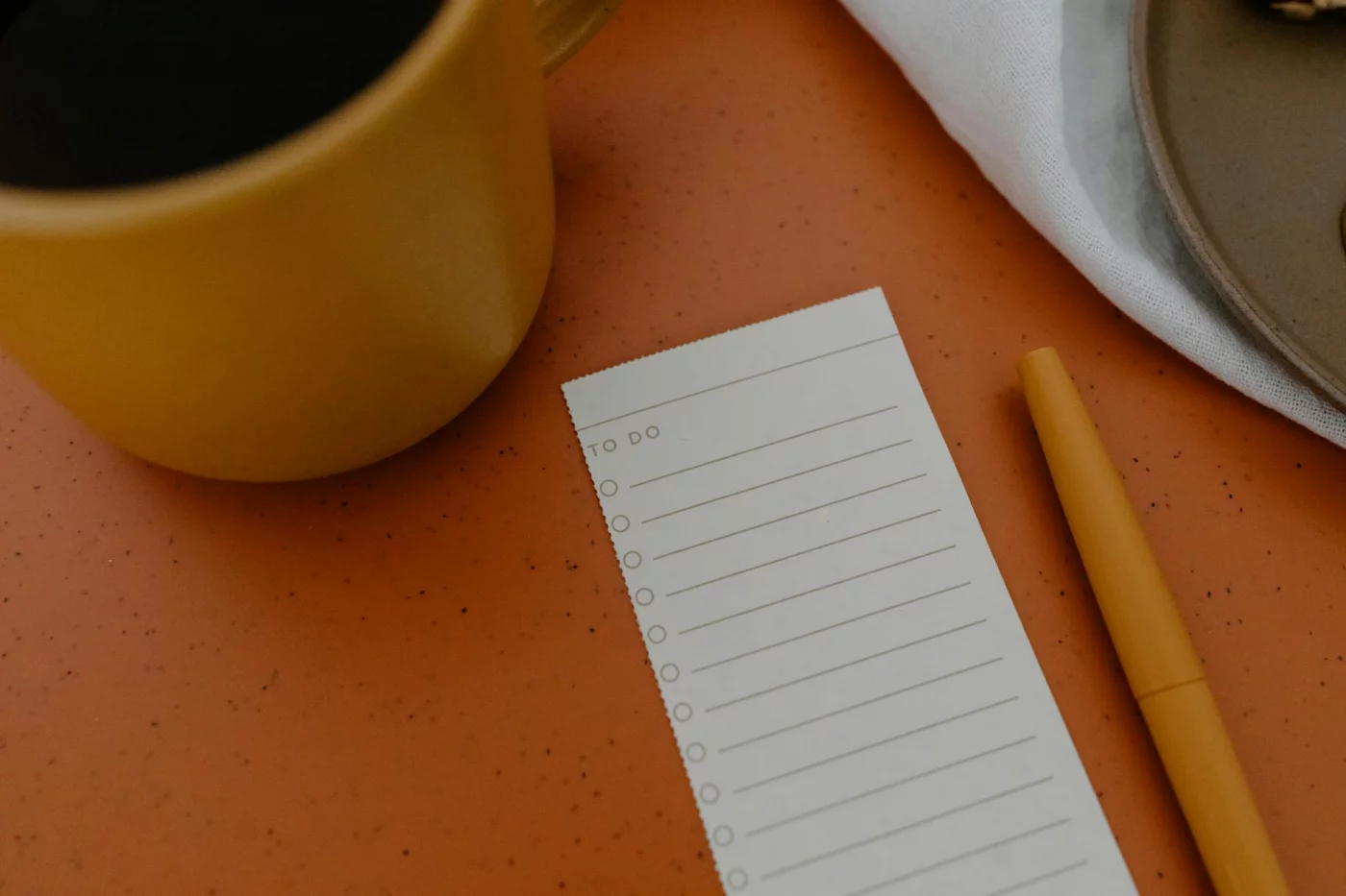 Quick reference on how to use 9 focus levers: mug, to-do list, and pen on orange desk checklist
