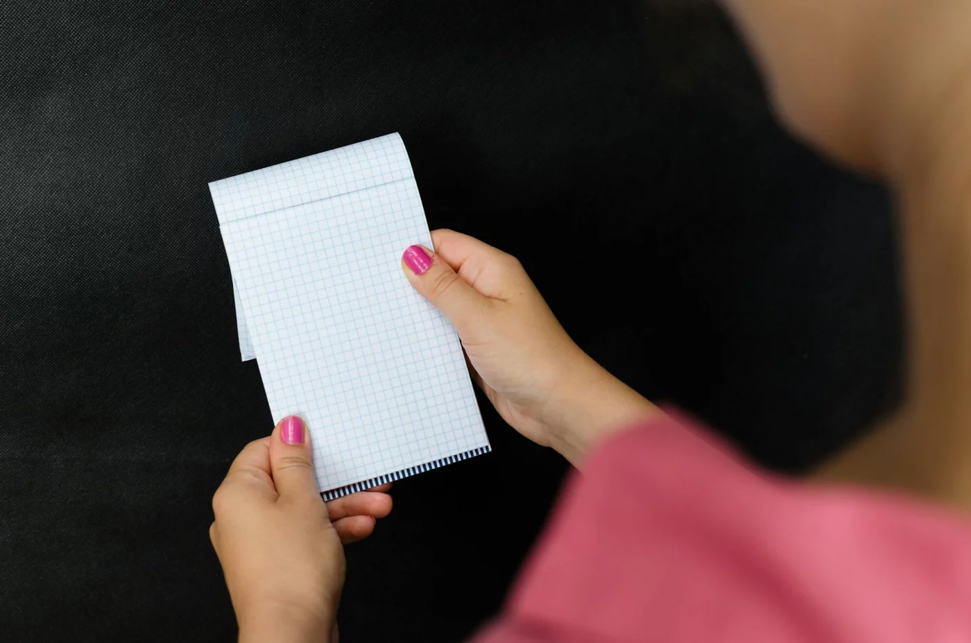 Woman holding a small checked notepad showing how to capture and link Zettelkasten smart notes in 9 steps