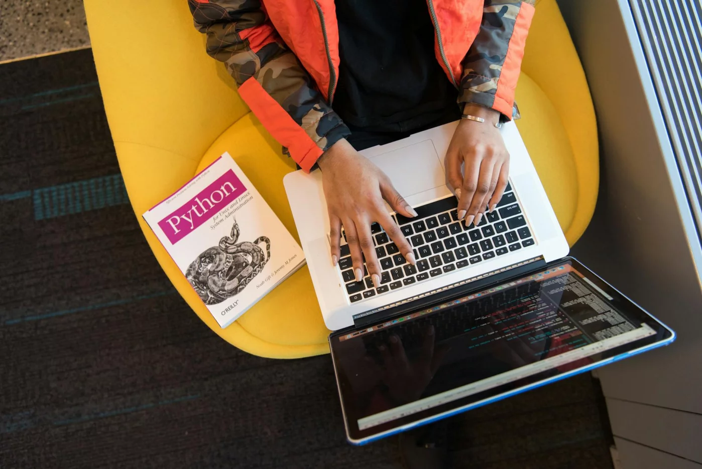 Developer coding on a laptop beside a Python book, illustrating how to learn python faster in 30 days