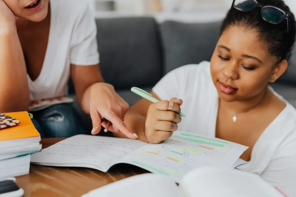 Two women studying with notes and pens, showing how to learn Spanish in 6 months through collaboration