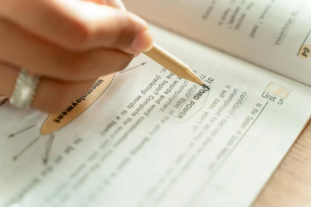 Woman writing notes in a textbook for how to make a study guide for an exam and improve exam prep