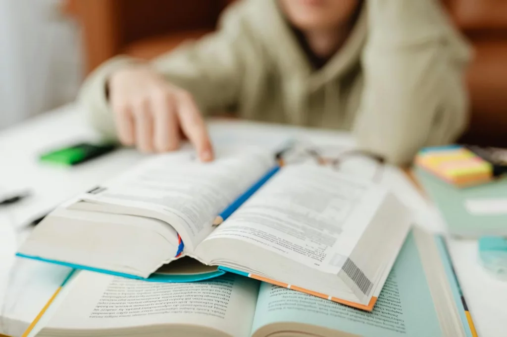Person pointing at an open book on a desk while learning how to read faster without losing comprehension