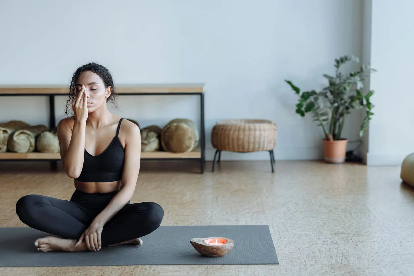 Woman meditating on a yoga mat with candle, showing how to reduce anxiety immediately through grounding