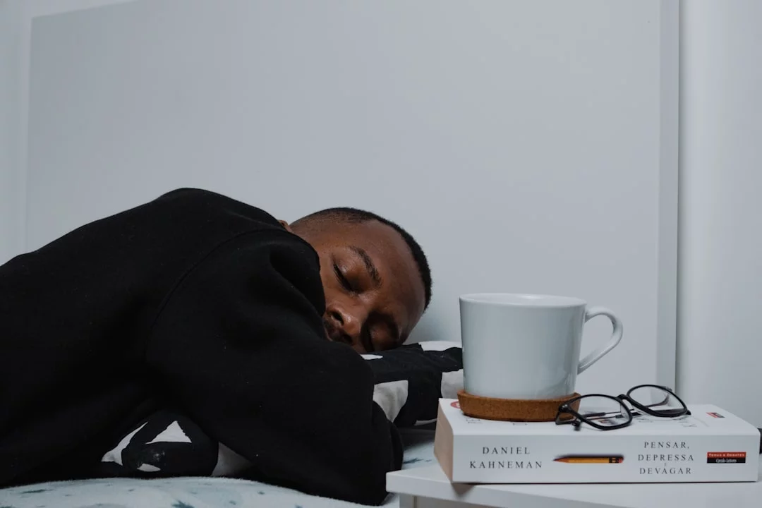 Man sleeping beside stacked books, illustrating how to sleep when stressed and anxious and spot sleep anxiety