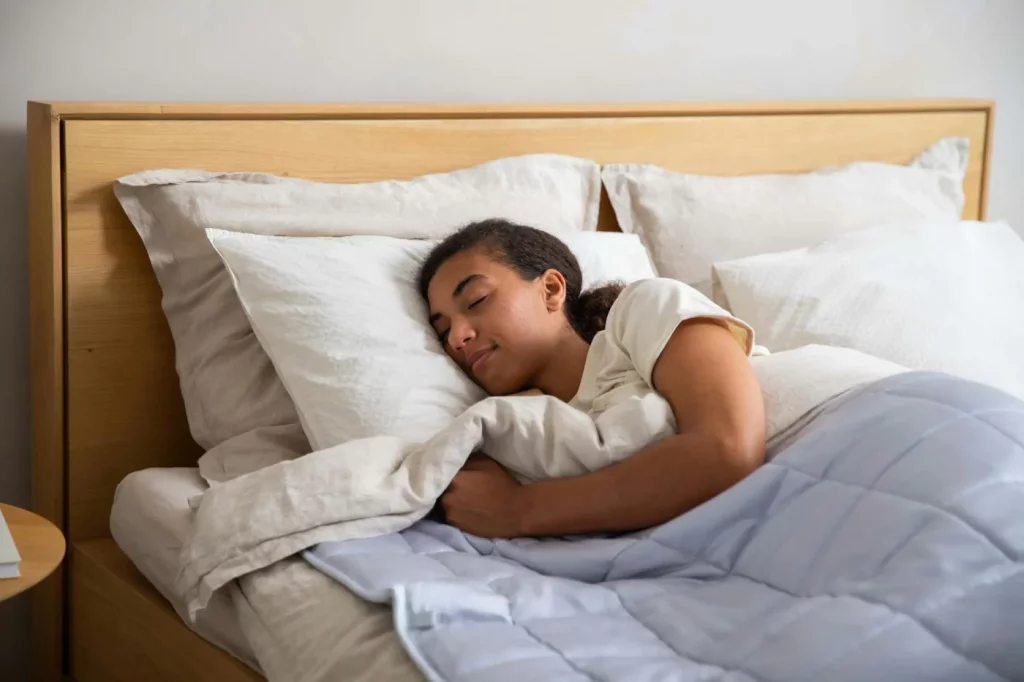 Adult resting under a cozy duvet in a serene bedroom, illustrating how to sleep with tinnitus more comfortably