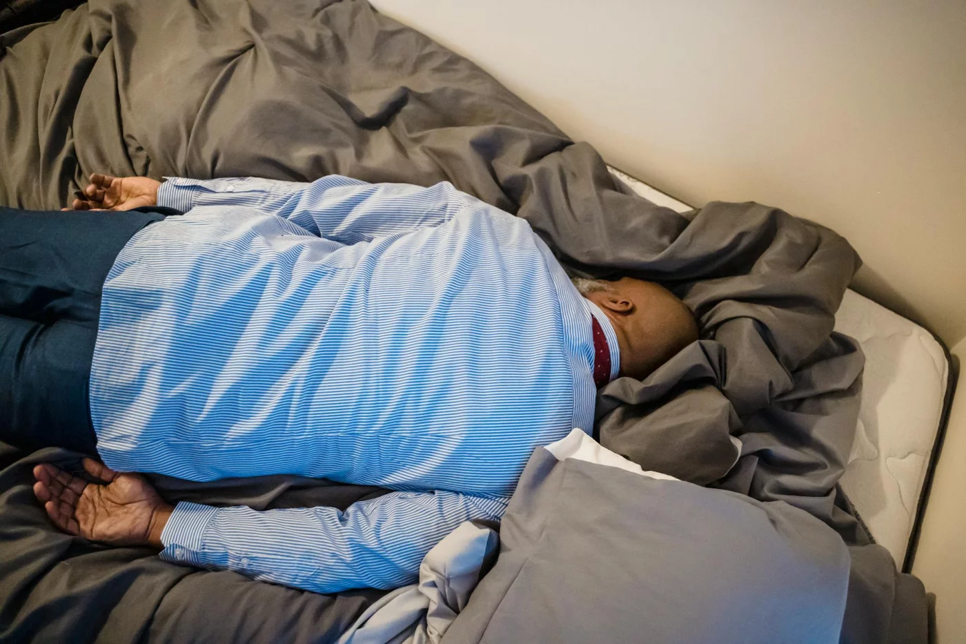 How to Sleep With Tinnitus: Practical Nighttime Strategies Exhausted man face down on bed shows common mistakes in how to sleep with tinnitus and worsening insomnia