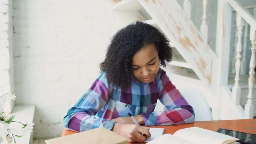 Student writing study notes at a table for how to study for sat in a month