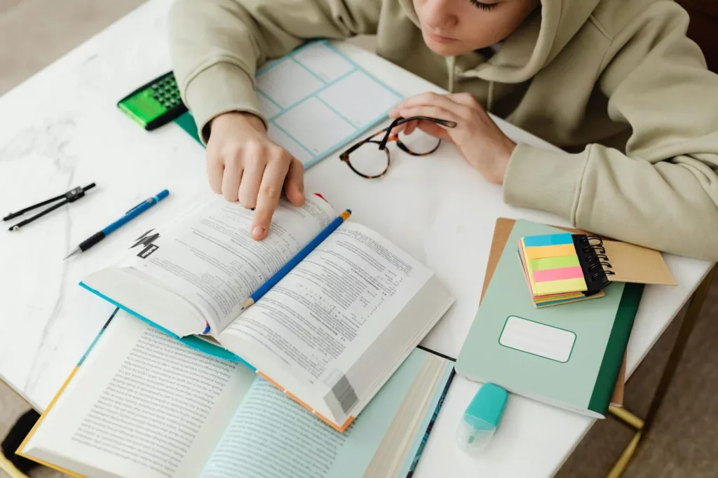 How to Take Notes From a Textbook Fast: 5 Methods That Actually Save Time Student studying with textbooks, calculator, and notes while learning how to take notes from textbook fast