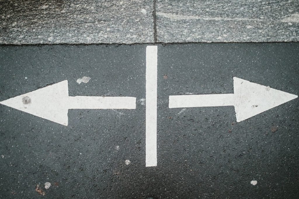 Two white arrows pointing opposite directions on asphalt, symbolizing how to trust yourself to make decisions
