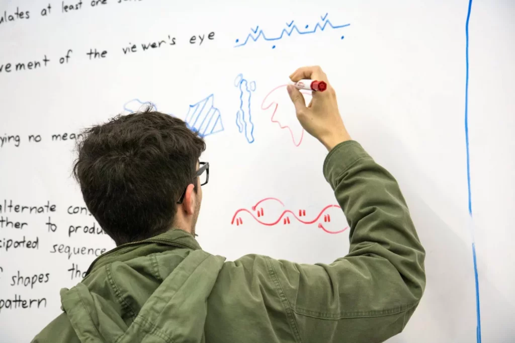Student drawing colorful diagrams on a whiteboard to explain how to use memory palace for exams effectively