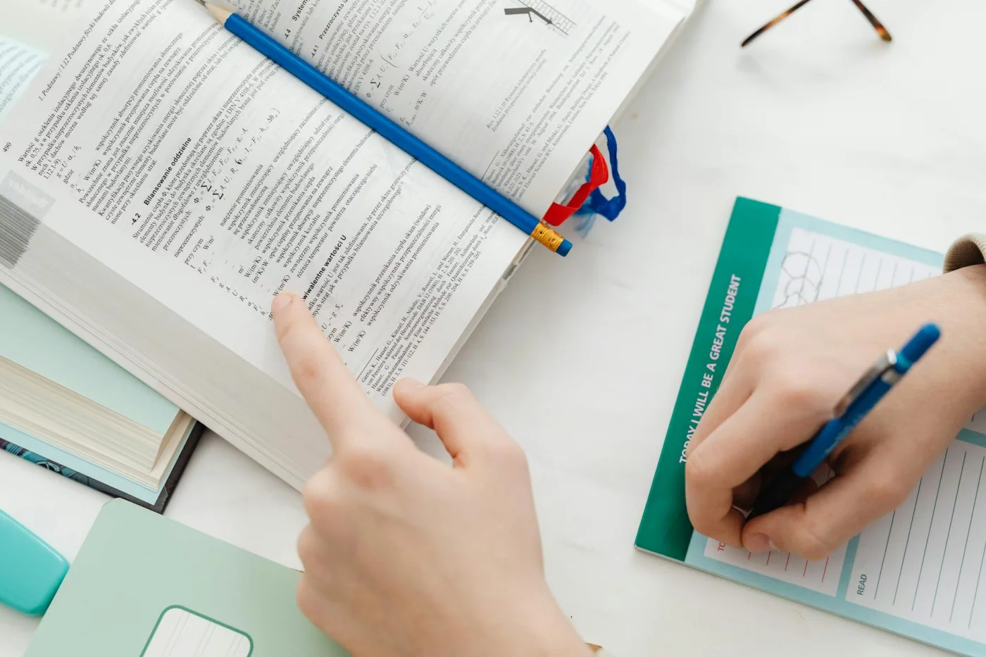 Student using notes and an open math book to test if is feynman technique effective for learning complex concepts