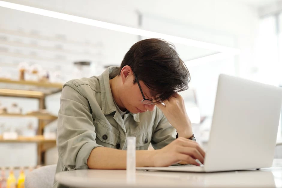 Exhausted man at laptop illustrating neuroscience based coping skills for stress and the brain’s stress response