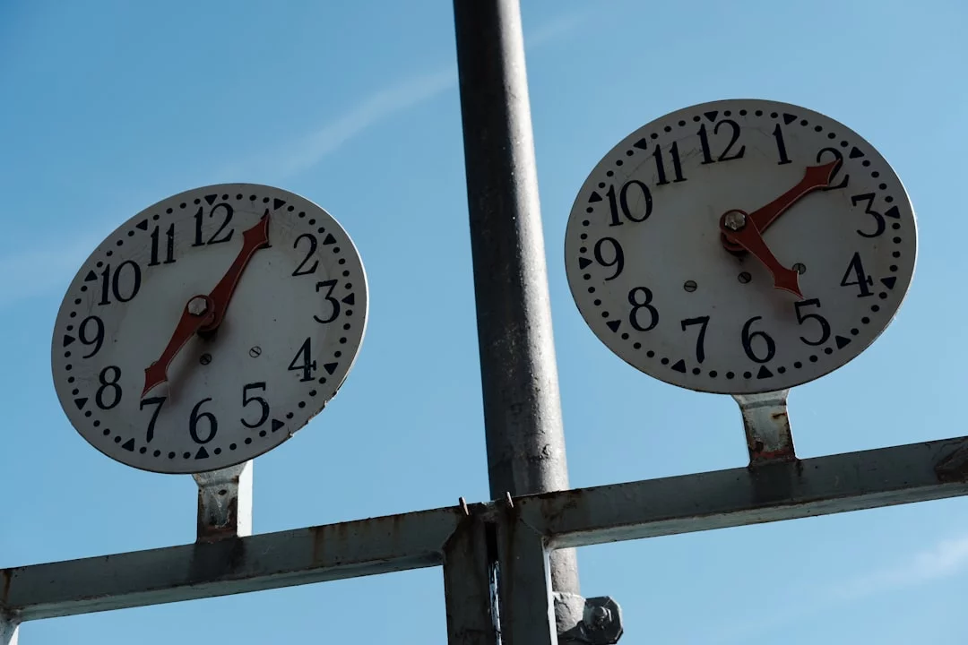 Two clocks showing different times in a blue sky illustrating personal energy management vs time management definitions