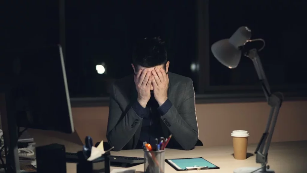 Professional feeling overwhelmed at desk, illustrating setting personal boundaries at work to reduce stress