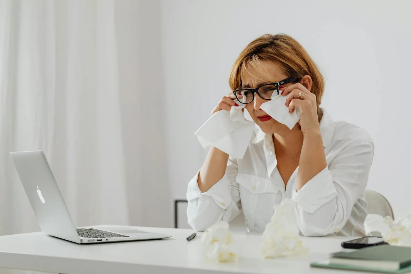 Woman stressed at laptop with tissues, illustrating setting personal boundaries at work to prevent burnout