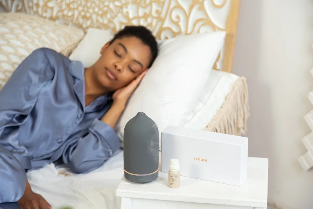 Tinnitus, Brain Fog, and Sleep: How They Connect Woman lying on a bed beside a nightstand, reflecting next-day recovery tips for tinnitus and brain fog