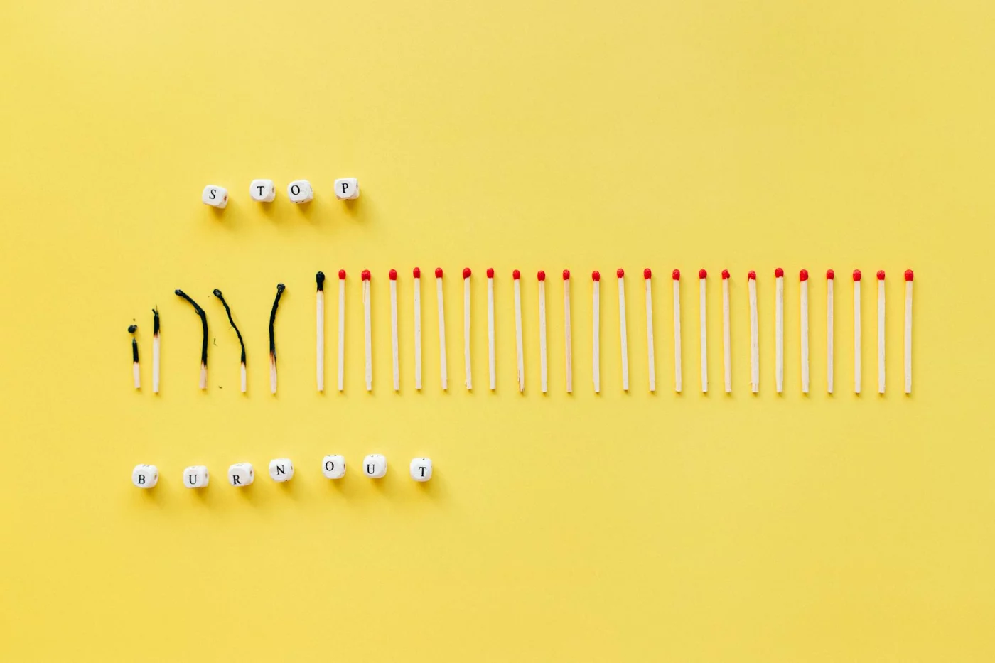 Burned and unburned matches on a yellow background spelling Stop Burnout, illustrating tips for burnout recovery