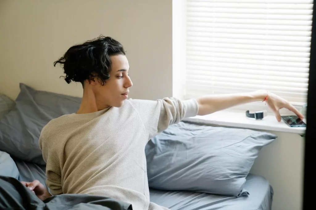 Student reaching for his phone after waking up, illustrating what is digital minimalism in daily life