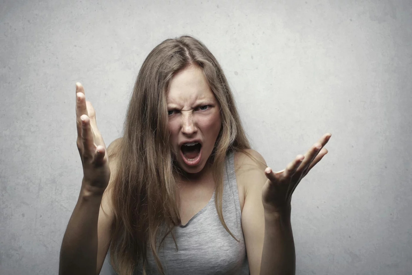 Angry woman yelling, illustrating why does stress make tinnitus worse through heightened central gain and louder perception
