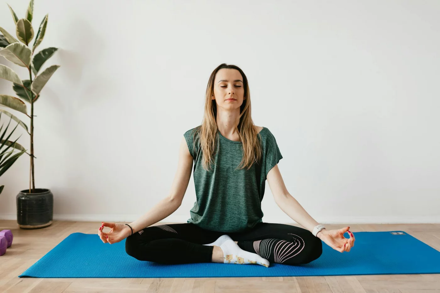 Woman meditating at home near plants, illustrating a 2 minute meditation script for fast stress relief