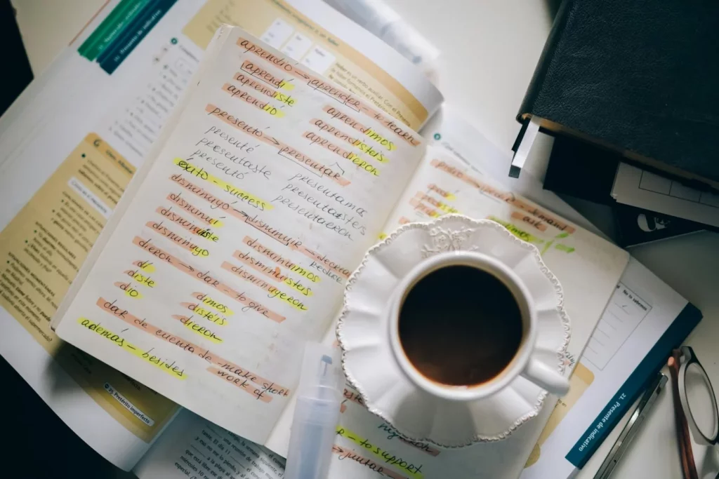 A Daily 20-Minute Language Routine for Busy Adults Coffee cup on handwritten Spanish notes, illustrating the 80 20 rule for learning spanish in a quick study session