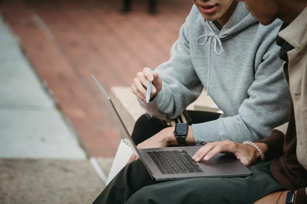 Anki vs SuperMemo vs RemNote: Which SRS App Fits You Best? Students collaborating with a laptop outdoors while researching anki vs remnote reddit for study app comparisons