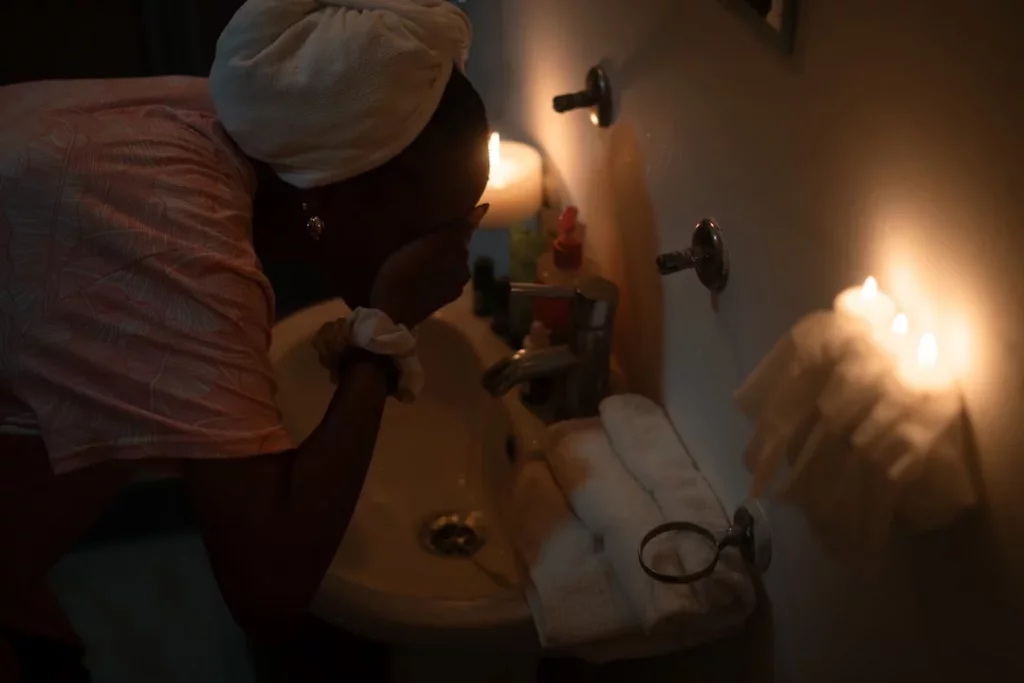 How to Build a Bedtime Routine for Adults That Helps You Fall Asleep Faster Woman washing her face by candlelight as part of a calming bedtime routine for adults